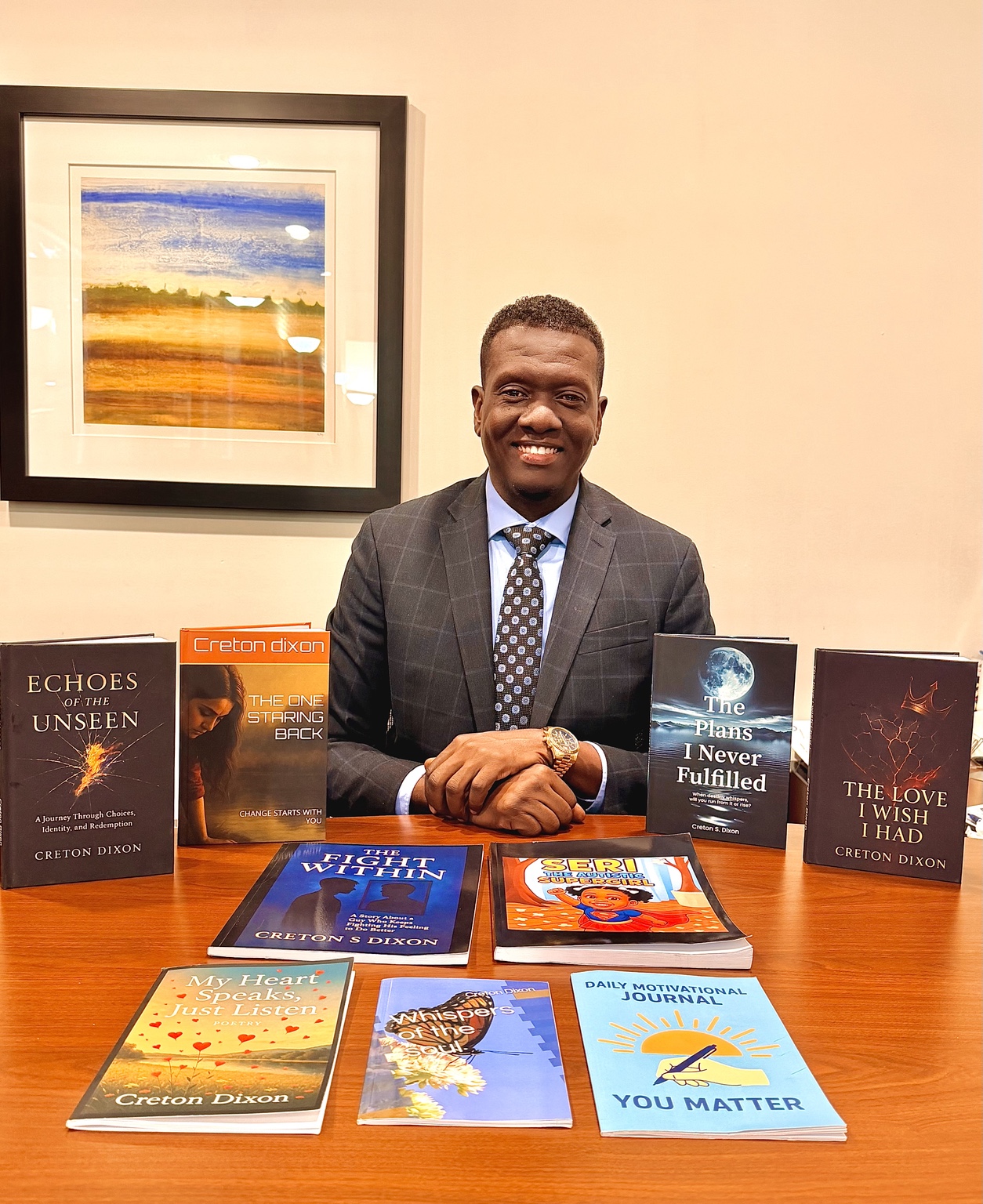 Creton Dixon smiling at a table surrounded by his published books